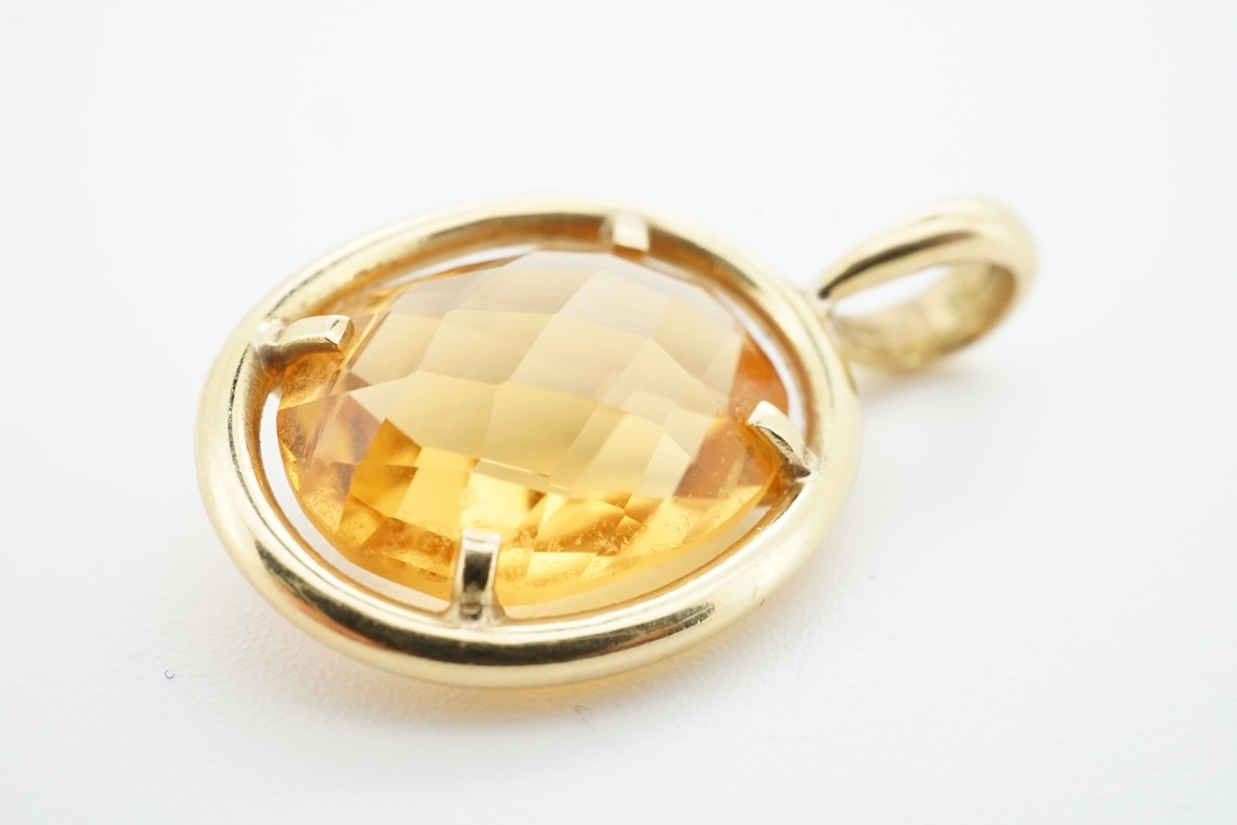 A modern yellow metal (stamped 750) and facet cut oval citrine set pendant, overall 27mm, gross weight 4.9 grams.